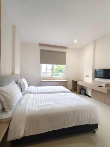 a large white bedroom with two beds and a television at Kawa Living in Krukah