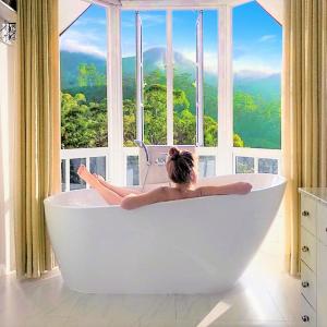 a woman laying in a bath tub in front of a window at Luxe Wilderness in Nuwara Eliya