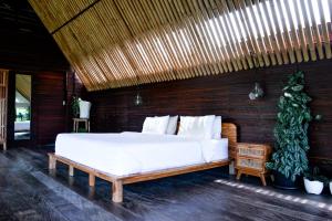 a bedroom with a large bed with a wooden wall at Let's Get Lost Ubud in Ubud