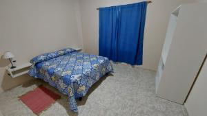 1 dormitorio con cama y cortina azul en Casa con pileta privada en General Alvear