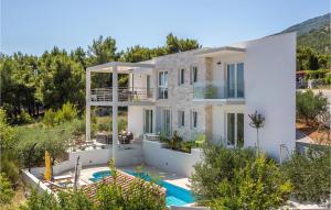 a large white house with a swimming pool and trees at Stunning Home In Bol With House A Mountain View in Bol
