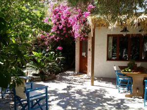 a patio with chairs and a table with pink flowers at Beautiful Cottage in S West Crete near the sea in Palaiochóra