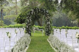 an aisle with white chairs and an arch with flowers at Handara Golf & Resort Bali in Bedugul