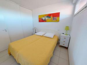 małą sypialnię z żółtym łóżkiem i szafką nocną w obiekcie Appartement 2 pièces avec accès direct plage, piscine et terrasse - Marseillan - FR-1-326-778 w mieście Marseillan