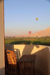 einen Tisch und Stühle auf einem Balkon mit einem Heißluftballon in der Unterkunft Twin rooms close to most tourist areas in Luxor