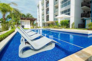 a swimming pool with lounge chairs next to a building at Playa Caracol, beach happy in Chame