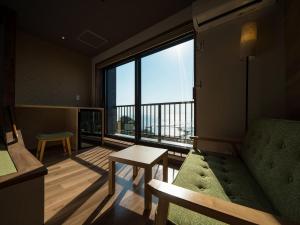 a living room with a couch and a large window at Iseebisou in Ibusuki