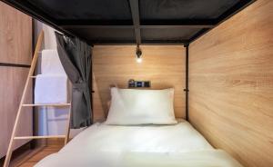 a small bed in a small room with wooden walls at Siam Subway Hostel and Café in Bangkok