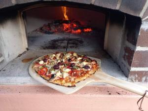 Uma pizza está a ser cozinhada num forno de tijolos. em Garden of Eden Boutique Cottage and Spa em Doonside