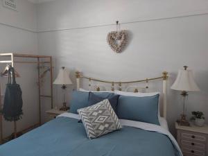 Un dormitorio con una cama azul con un corazón colgando en la pared en Garden of Eden Boutique Cottage and Spa en Doonside
