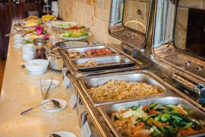 a buffet with many trays of food on a table at Liberty Hall Tam Coc Hotel & Villa in Ninh Binh