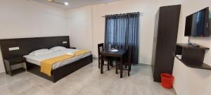 a bedroom with a bed and a desk and a television at Thekkady Travel Rooms in Thekkady
