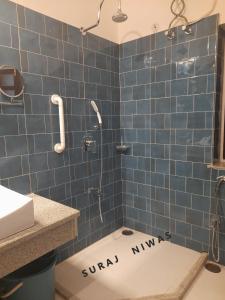 baño de azulejos azules con ducha y aseo en Suraj Niwas, en Jaipur