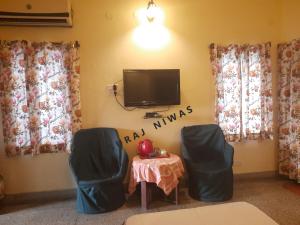 Habitación con 2 sillas y mesa con TV. en Suraj Niwas, en Jaipur