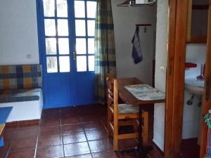a room with a blue door and a table and a sink at S West Crete Cottage in Palaiochóra