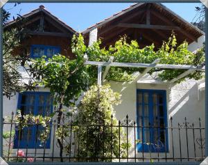 Exclusive Cottage in S West Crete in a quiet olive grove near the sea في باليوخورا: بيت أبيض بنوافذ زرقاء وسياج