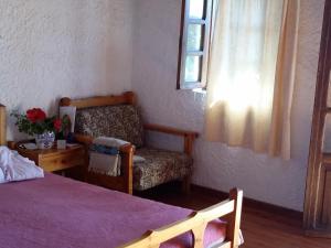 um quarto com uma cama, uma cadeira e uma janela em Amazing Cottage close from the sea - Crete em Palaiochora