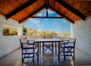 a table and chairs on a porch with a large window at Exclusive Cottages are in S West Crete in a quiet olive grove near the sea in Palaiochóra