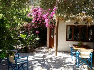 a patio with chairs and a tree with pink flowers at Exclusive Cottages are in S West Crete in a quiet olive grove near the sea in Palaiochora