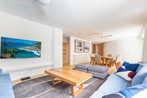 un soggiorno con un divano blu e un tavolo di The Cove Noosa - Apartment 11 a Noosa Heads