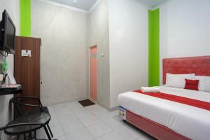 a bedroom with a bed with green and red accents at RedDoorz Syariah near RS Advent Bandar Lampung in Bandar Lampung