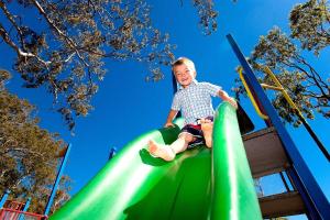 a young boy riding on a slide at a playground at BIG4 Lucinda Wanderers Holiday Park in Lucinda
