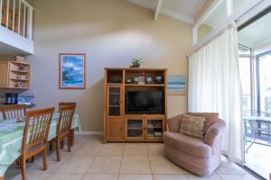 a living room with a television and a dining table at Paniolo Condo in Kahuku