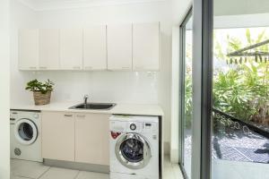 cocina blanca con lavadora y fregadero en Cairns Beaches Home, Marina View, Sleeps 12 en Yorkeys Knob