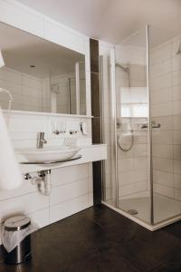 a white bathroom with a sink and a shower at Dorfgasthof Adler in Mellau