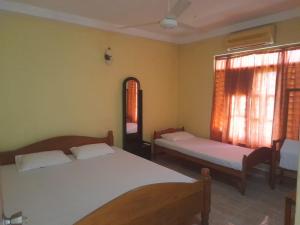 sypialnia z 2 łóżkami i oknem w obiekcie Green Parrot Family Resort w mieście Polonnaruwa