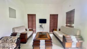 a living room with two couches and a coffee table at Mountain Mansion Kodai in Kodaikānāl