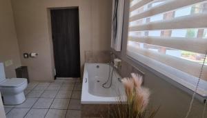 baño con lavabo y aseo y ventana en Heimat Guesthouse, en Welkom
