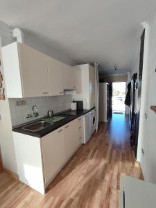 a kitchen with white cabinets and a wooden floor at Apto. residencial en Torremolinos con piscina. in Torremolinos