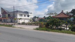 a street with a white building and a house at Hotel Wisma Mangurna in Doloksanggul