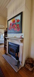 a fireplace in a living room with a painting on the wall at Amiens Cottage. Queenslander, charming, central. in Stanthorpe