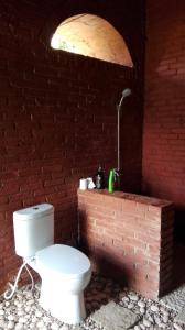 baño con aseo y pared de ladrillo en Havana Horses Lodge en Tingkirtengah
