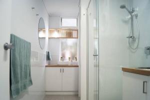 een witte badkamer met een wastafel en een douche bij Heart @ Heidelberg in Heidelberg