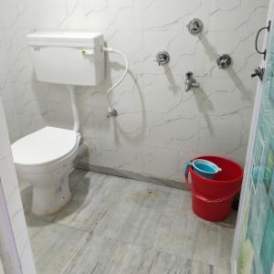 ein Badezimmer mit einem WC und einem roten Eimer in der Unterkunft Deep Home stay in Agartala