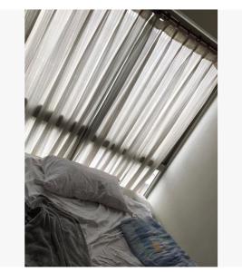 ein Bett vor einem Fenster mit einem Vorhang in der Unterkunft Hogar dulce hogar in Mexiko-Stadt