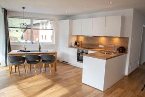 een keuken met witte kasten en een tafel en stoelen bij Veranda Appartement Bergblick in Gries im Sellrain