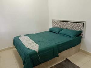 a bed with a green comforter in a bedroom at Rumah Cikgu 3bilik tidur in Jitra +8 photos