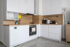 a white kitchen with white cabinets and appliances at Rent-Apart City Center Narutowicza in Łódź
