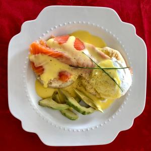 a white plate with a piece of fish and vegetables at Winston Cottage in Palmwoods