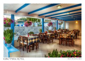 un restaurante con mesas de madera, sillas y flores en Euro Park Hotel, en Astris