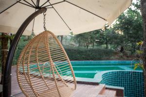a wicker chair hanging from an umbrella next to a pool at U Maerim Chiangmai - อยู่แม่ริม เชียงใหม่ in Mae Rim