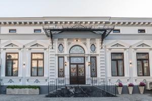 een groot wit gebouw met een deur en een trap bij SIR LUXURY BOUTIQUE HOTEL in Brăila