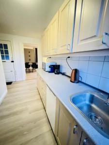 uma cozinha com armários brancos e um lavatório em aday - Modern 1 Bedroom Charming Central Apartment with Public Parking em Aalborg