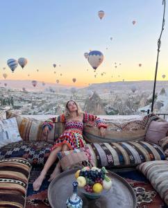 una mujer sentada en un sofá con globos en el cielo en Arif Cave Hotel, en Göreme