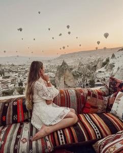 a woman sitting on a couch looking at the city at Arif Cave Hotel in Goreme