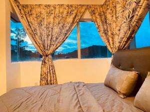 a bed in front of a window with a view at The Misty Penthouse in Tanah Rata
